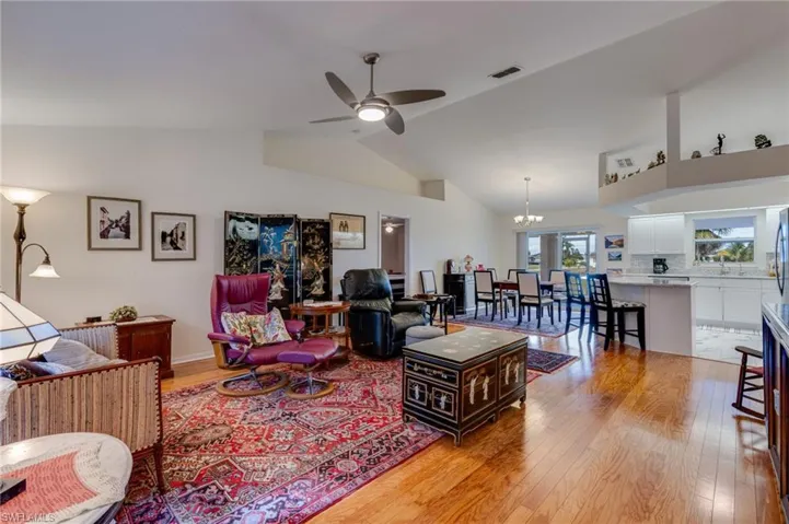 Living area with a chandelier, a ceiling fan, light wood-style floors, and high vaulted ceiling