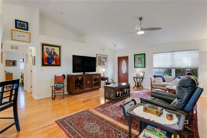 Living room with light wood finished floors, a ceiling fan, and high vaulted ceiling