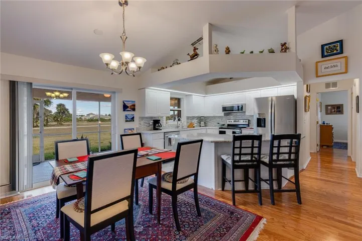 Dining space with a chandelier, light wood finished floors, and high vaulted ceiling