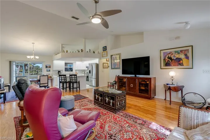 Living room with a chandelier, a ceiling fan, light wood-type flooring, and high vaulted ceiling