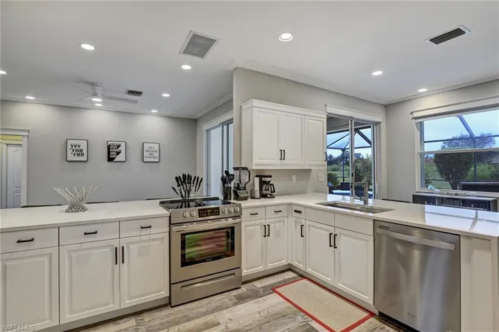 Kitchen with stainless steel appliances, white cabinets, light wood-style floors, recessed lighting, and light stone countertops