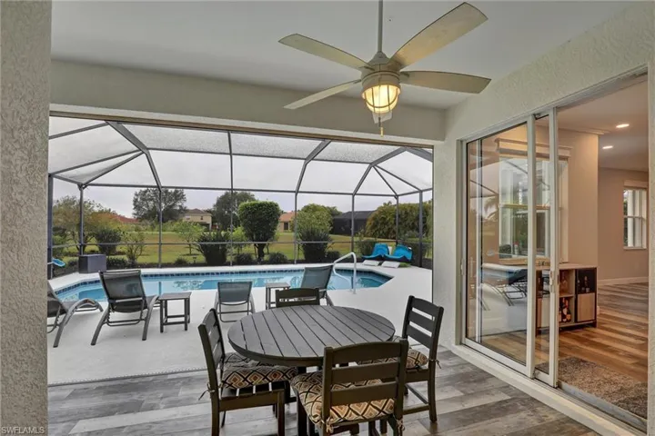 View of patio / terrace featuring a sunroom, an outdoor pool, glass enclosure, a ceiling fan, and outdoor dining space