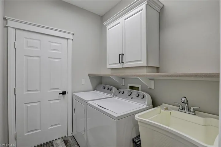 Laundry area with cabinet space, washing machine and clothes dryer, and wood finished floors