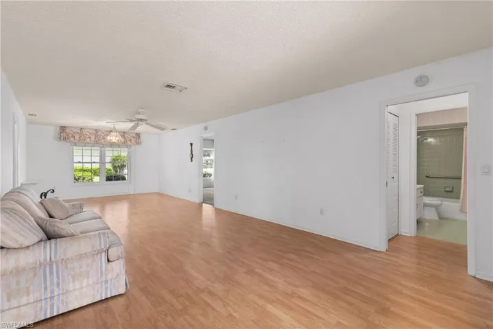 Living area featuring ceiling fan, light wood-type flooring, and a textured ceiling