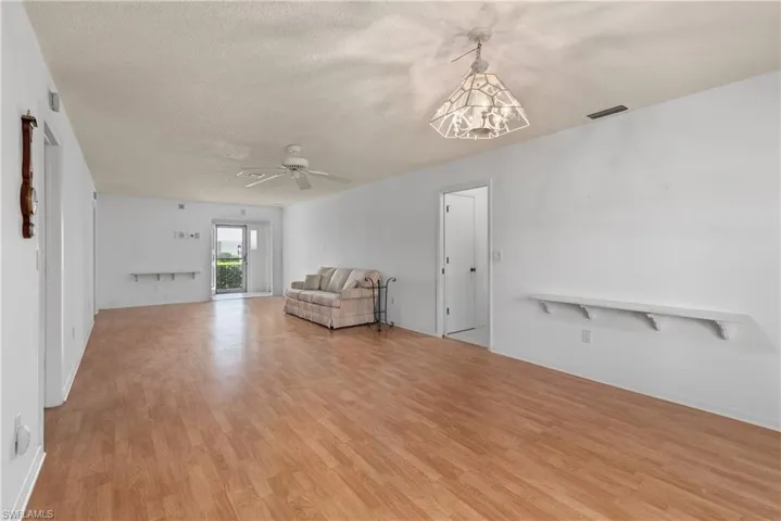 Unfurnished room featuring light wood-type flooring, a chandelier, a ceiling fan, and a textured ceiling