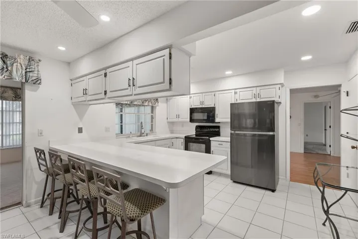 Kitchen with black appliances, light countertops, a sink, a peninsula, and recessed lighting