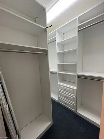 Walk in closet featuring dark colored carpet