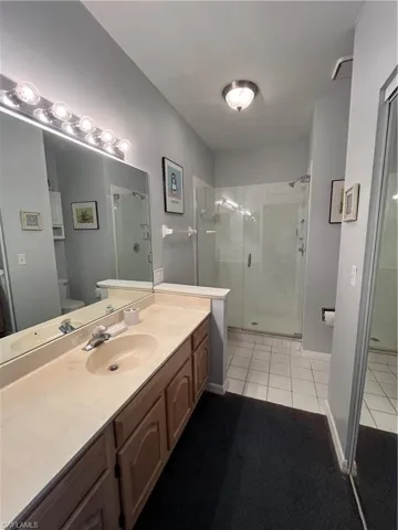 Bathroom featuring a shower with shower door, toilet, tile patterned floors, and vanity