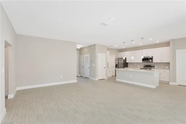 Kitchen with white cabinetry, a kitchen island with sink, stainless steel appliances, hanging light fixtures, and sink