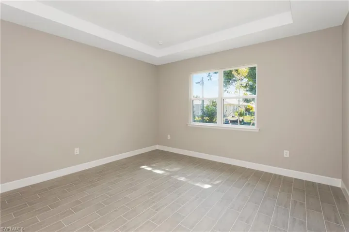 Empty room with light hardwood / wood-style flooring and a raised ceiling