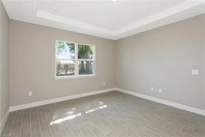 Unfurnished room featuring light wood-type flooring and a tray ceiling