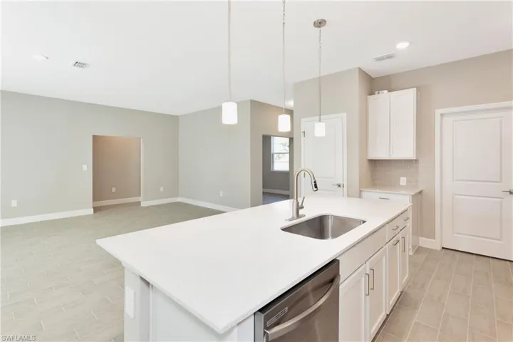 Kitchen with white cabinetry, dishwasher, an island with sink, decorative backsplash, and sink