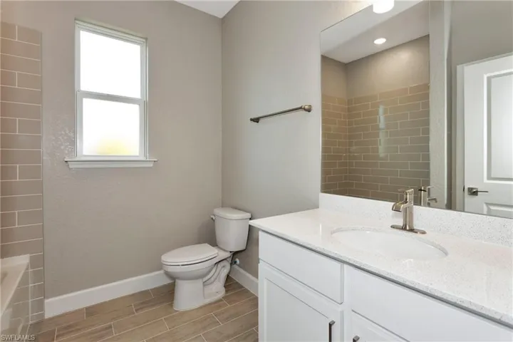 Full bathroom featuring vanity, tile patterned floors, a healthy amount of sunlight, and toilet
