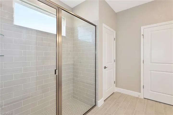 Bathroom featuring a shower with shower door and tile patterned flooring