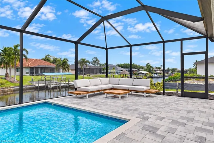 Screened-in lanai with a rectangular pool, paver patio, and canal frontage