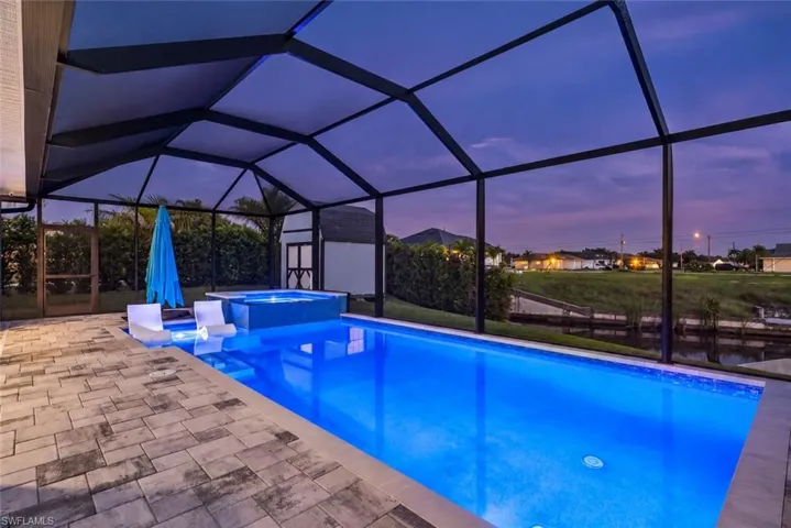 Screened-in outdoor area with a swimming pool, integrated spa, and paver decking