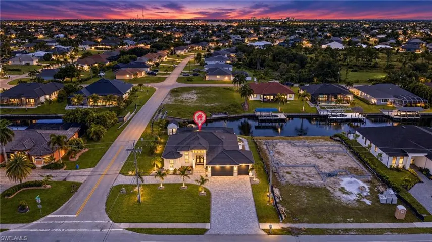 Paved driveway and walkway leading to the front entry, two-car garage, and mature landscaping