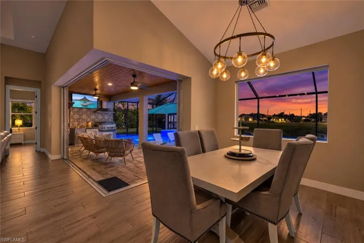 Dining area with vaulted ceilings, wood-finish flooring, and a multi-bulb chandelier