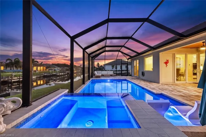 Expansive screened lanai featuring a swimming pool, integrated spa, and spacious paver deck