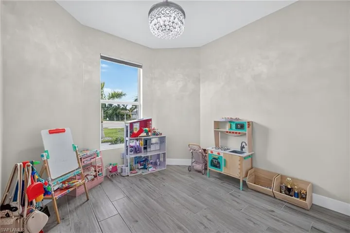 Recessed window with white trim, wood-look tile flooring, and a crystal chandelier