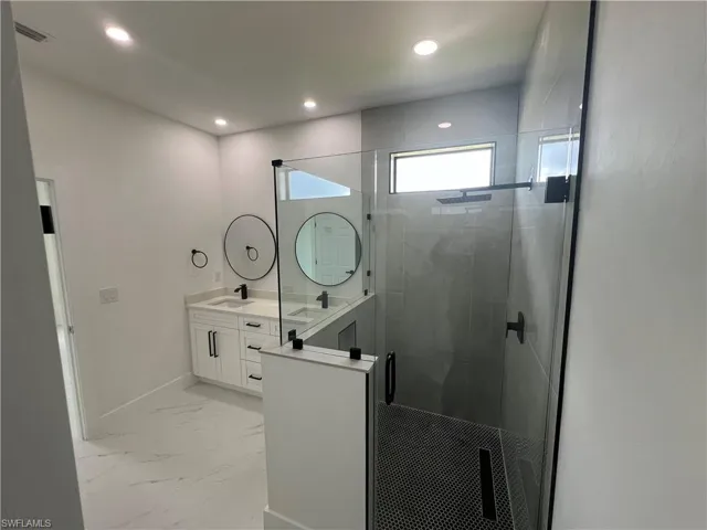 Bathroom with a shower with shower door, vanity, and tile patterned flooring