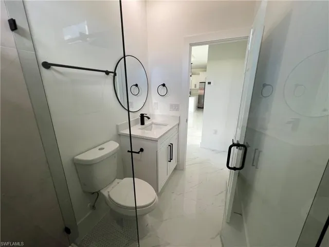 Bathroom featuring walk in shower, vanity, toilet, and tile patterned flooring