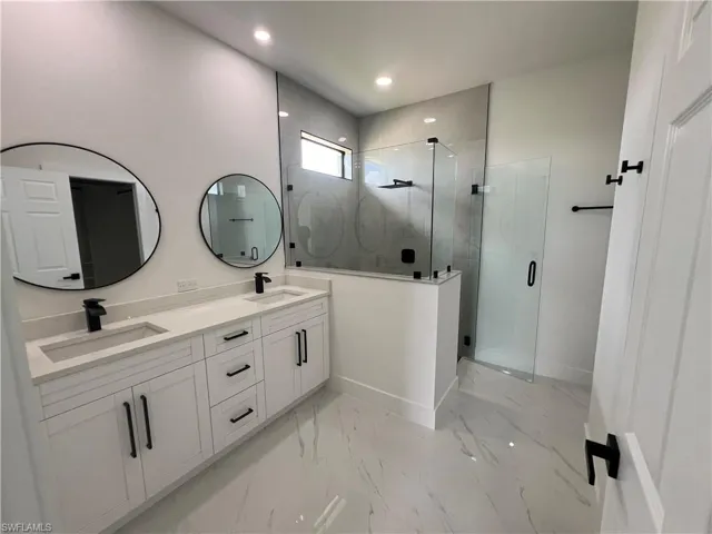Bathroom with double sink vanity, tile patterned flooring, and an enclosed shower