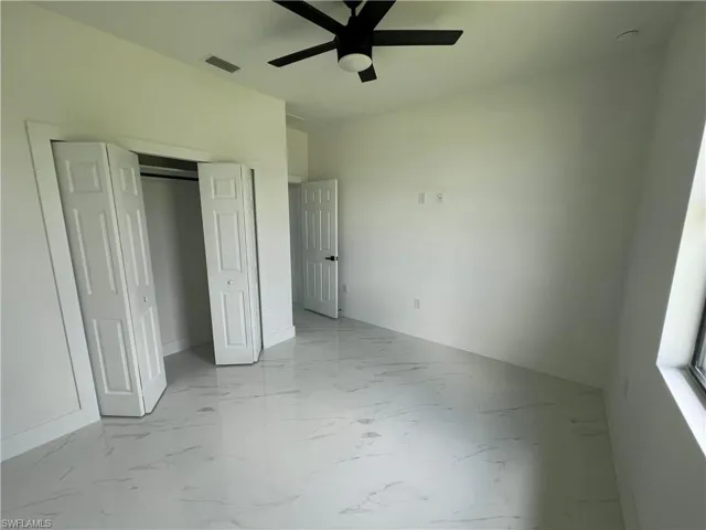 Unfurnished bedroom with ceiling fan, light tile patterned flooring, and a closet