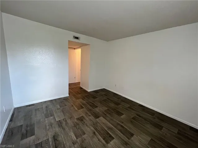 Spare room featuring dark wood-type flooring