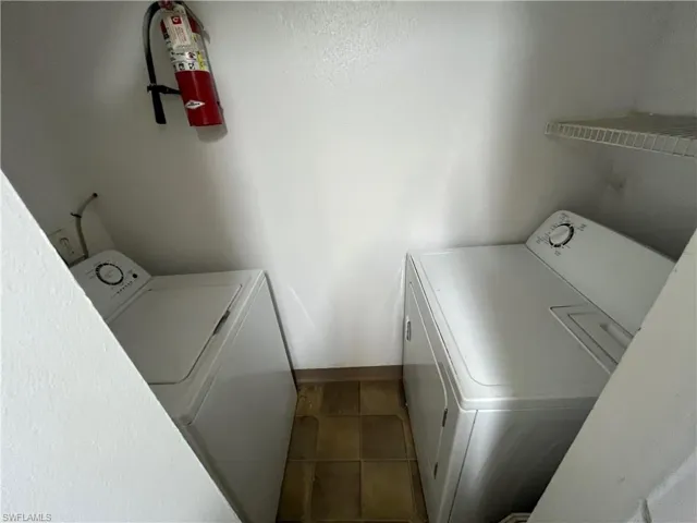 Laundry area featuring tile patterned flooring and washing machine and clothes dryer