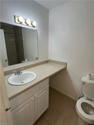 Bathroom featuring a shower, vanity, toilet, and tile patterned floors
