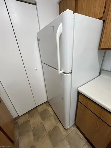 Kitchen with light tile patterned floors and white fridge