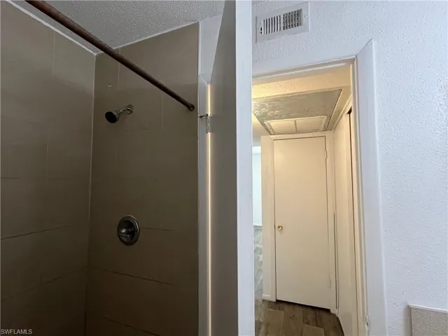 Bathroom featuring a textured ceiling, hardwood / wood-style floors, and a tile shower