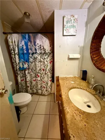 Bathroom featuring vanity, light tile patterned floors, and a shower with shower curtain