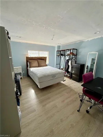 Bedroom featuring an office area and light wood finished floors