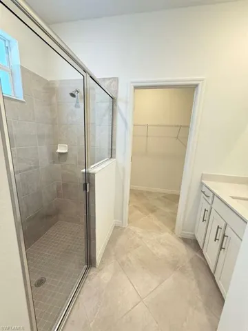 Full bath with vanity, a spacious closet, and a stall shower