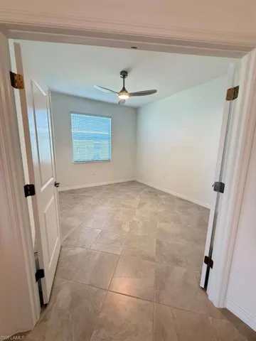 Empty room featuring baseboards and a ceiling fan