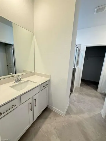 Full bath with a shower stall, a spacious closet, vanity, and a textured wall