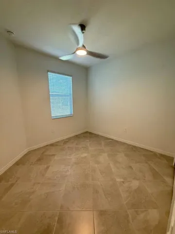 Empty room featuring baseboards and a ceiling fan
