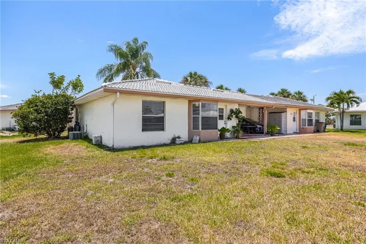 Back of property with a yard, a tiled roof, stucco siding, and cooling unit