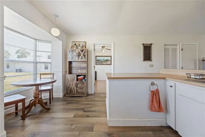 Kitchen with ceiling fan, dark wood-style floors, white cabinetry, light countertops, and pendant lighting