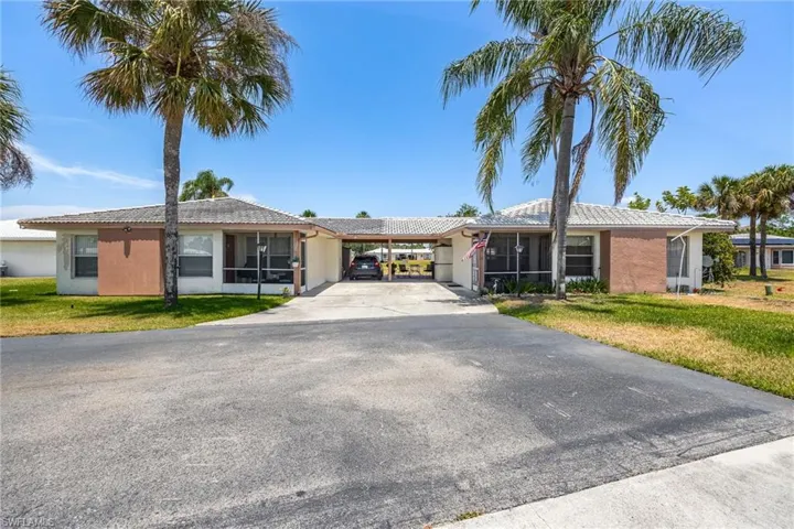 Ranch-style home featuring stucco siding, driveway, a front lawn, and an attached carport