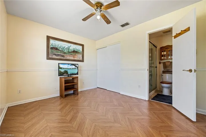 Unfurnished bedroom featuring connected bathroom, a closet, baseboards, and a ceiling fan
