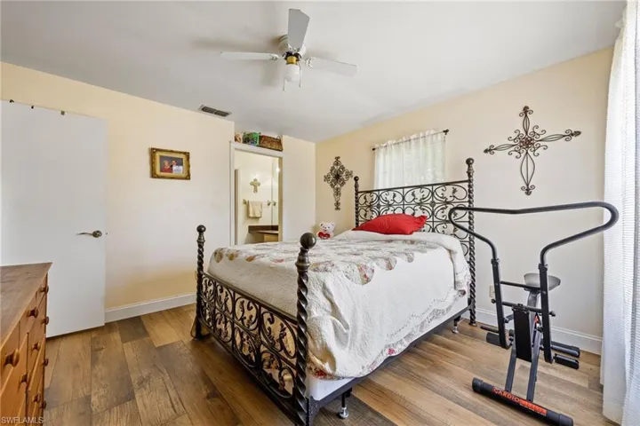 Bedroom with wood finished floors, baseboards, a ceiling fan, and connected bathroom