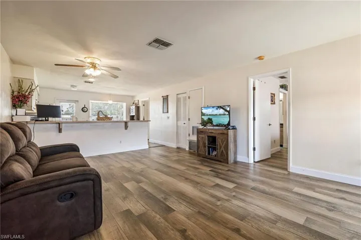 Living area with a ceiling fan, wood finished floors, and baseboards