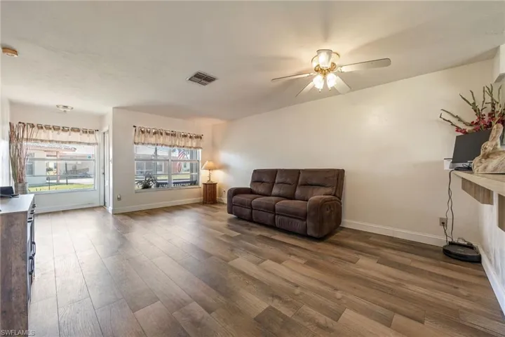 Living room with a ceiling fan, wood finished floors, and baseboards