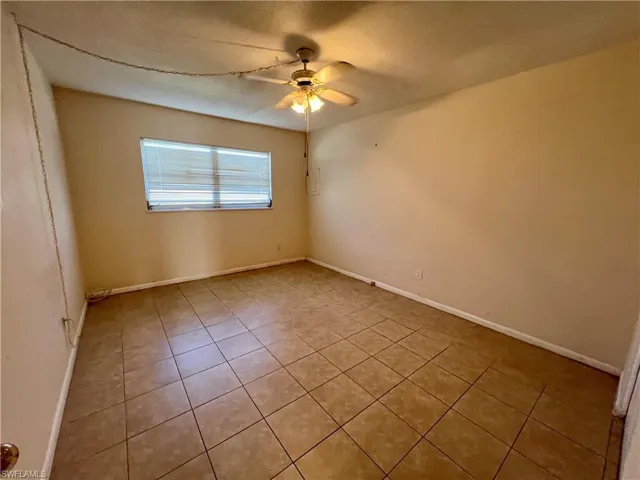 Tiled primary bedroom featuring ceiling fan