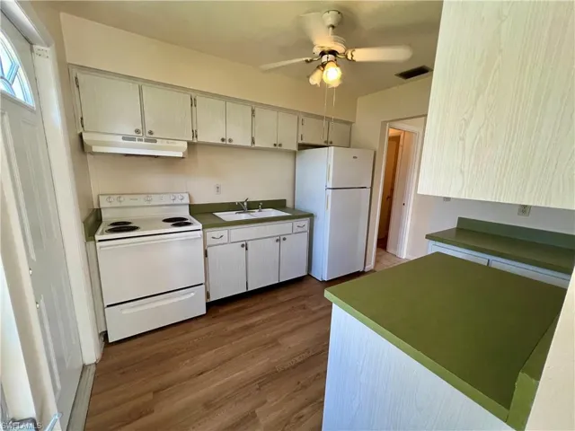 Kitchen featuring white appliances, cream cabinets, sink, and ceiling fan