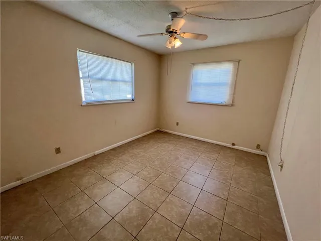 Tiled guest bedroom featuring ceiling fan, a textured ceiling, and a wealth of natural light
