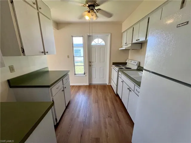 Kitchen featuring white cabinets, white appliances and ceiling fan